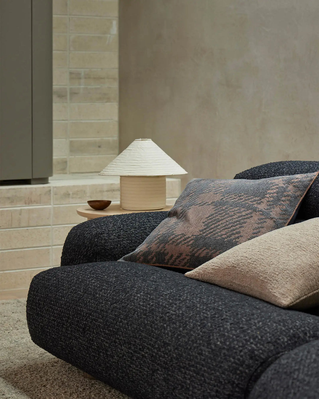 Neutral minimalist bedroom with layered Sienne cushions in charcoal and warm taupe tones, textured linen fabrics, and soft lighting—earthy palette bedroom styling