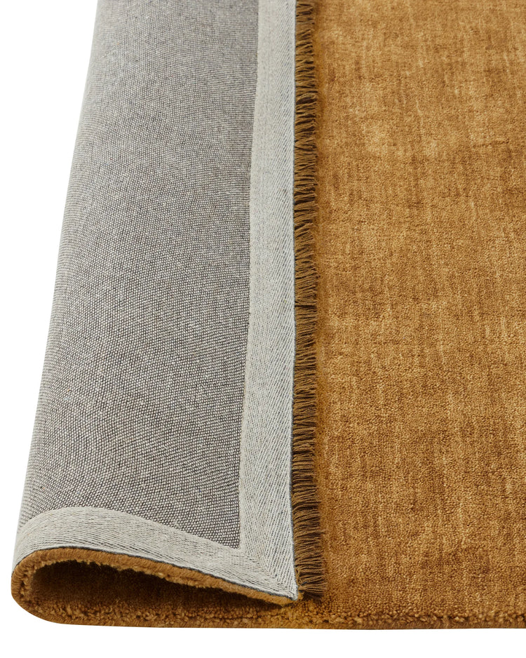 Silvio Dijon rug detail showing mustard wool pile with grey binding and micro fringe border, sustainable styling by Weave Home