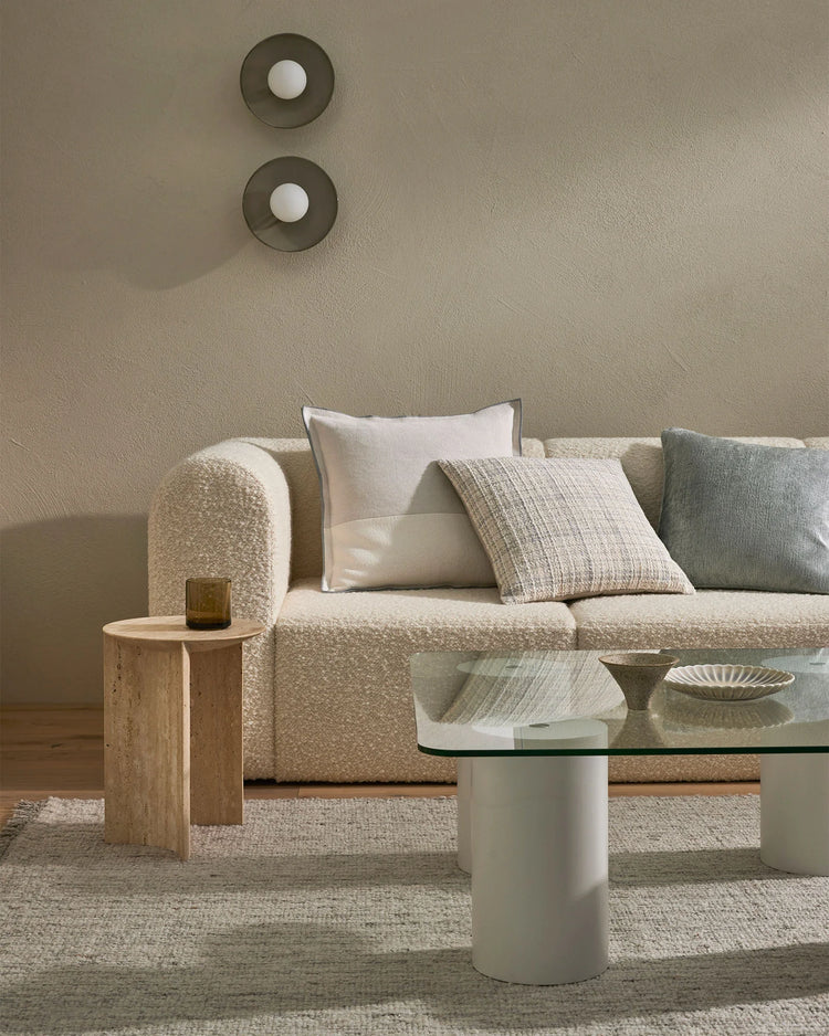 Neutral living room with textured linen sofa styled with Tempo cushions in cream and sage, natural timber side table, and layered area rug in warm beige tones