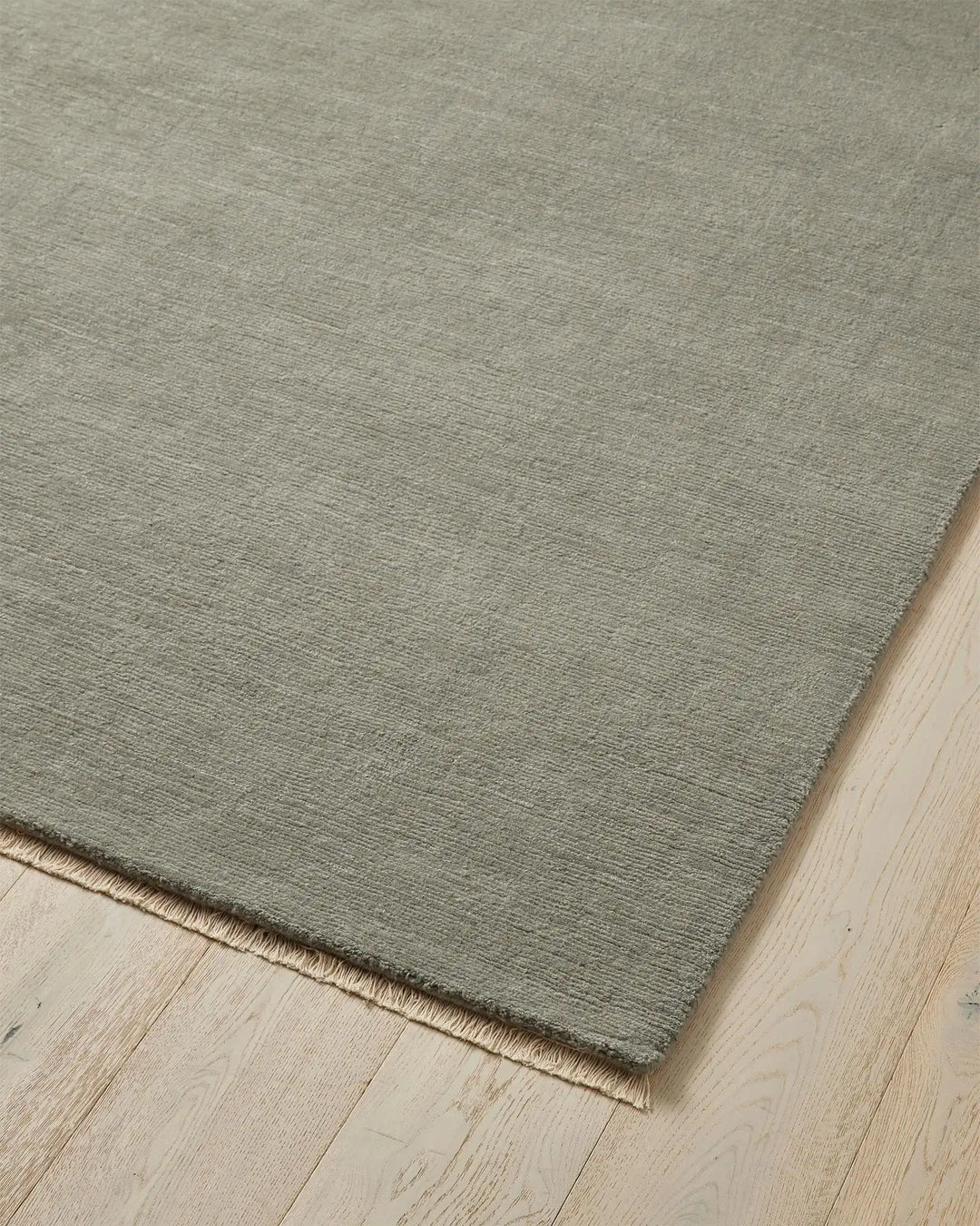 Alessandre Mineral rug corner detail showing soft grey-blue hand-woven NZ wool with natural fringe edge by Weave Home
