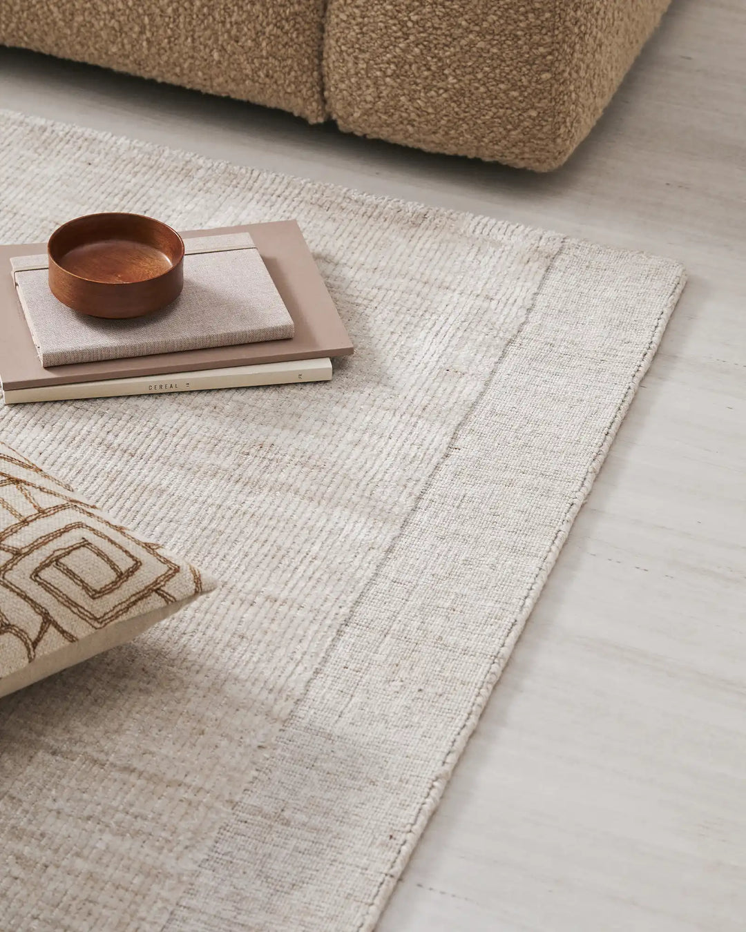 Neutral living room styled with Travertine Buff rug in soft cream textured viscose, layered with warm terracotta ceramics and natural wood tones against a tan upholstered sofa
