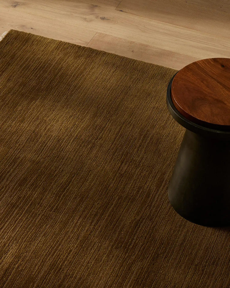 Alessandre rug in warm ochre tones layered on pale oak flooring, styled with timber furniture and minimalist décor for an earthy, contemporary aesthetic