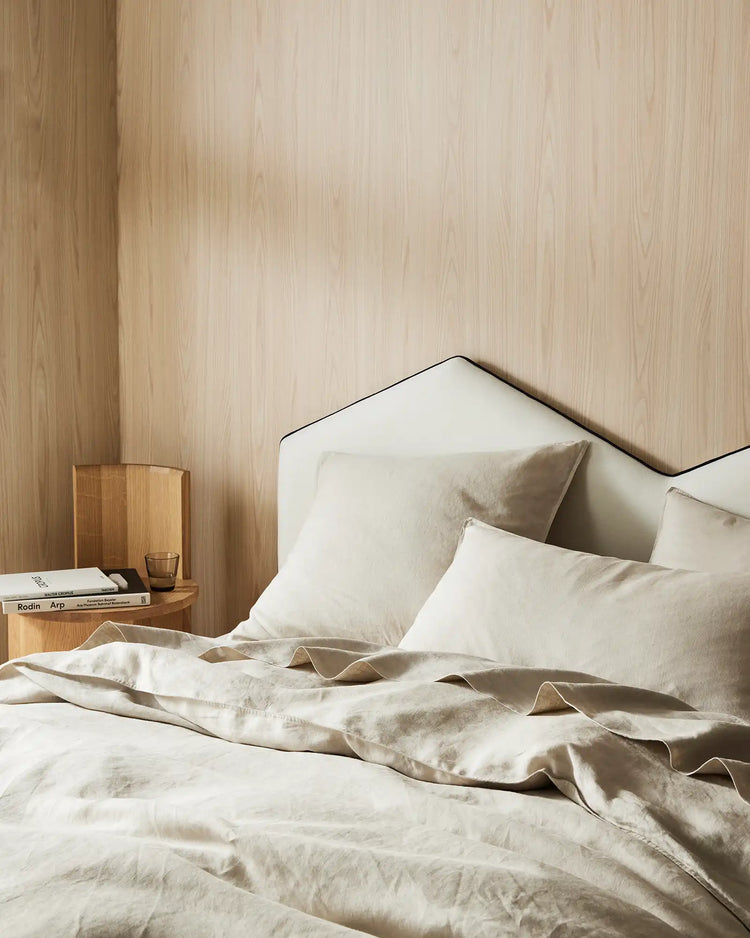 Minimalist bedroom with Ravello linen bedding in bone, styled on a bed with black metal frame against light wood paneling, natural texture and relaxed aesthetic