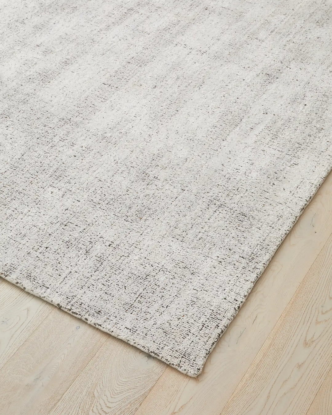 Matisse Marble rug corner view, light grey viscose blend with salt-and-pepper marled weave and cotton braided edge by Weave Home