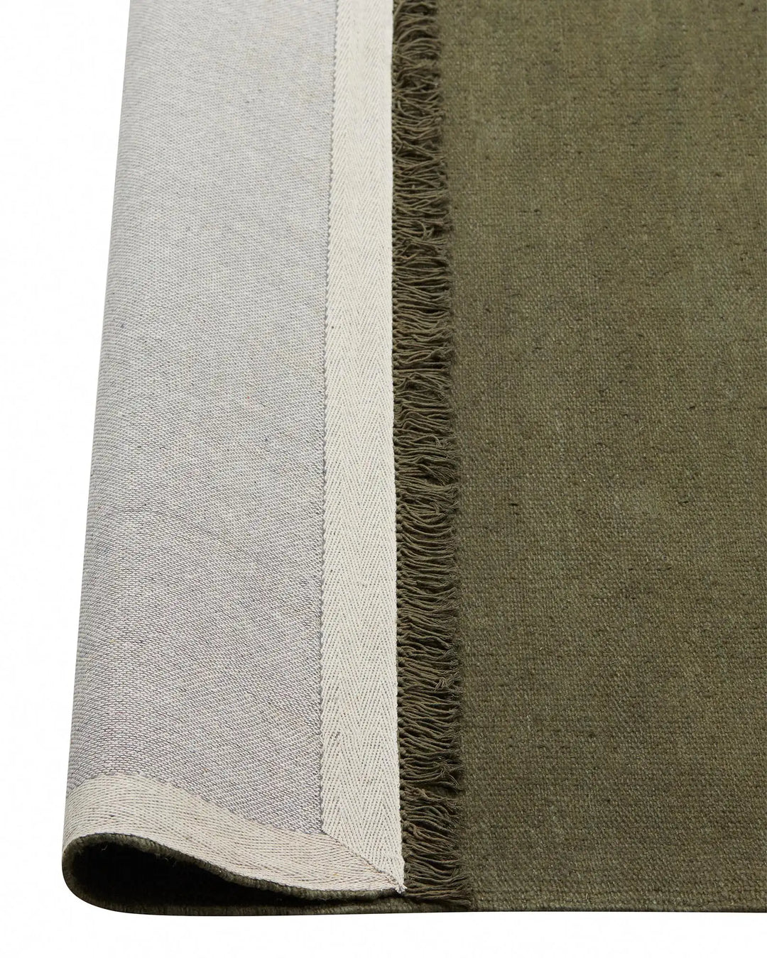 Emilio Kale linen rug detail showing deep forest green weave with cream fringe border, flat-weave construction by Weave Home