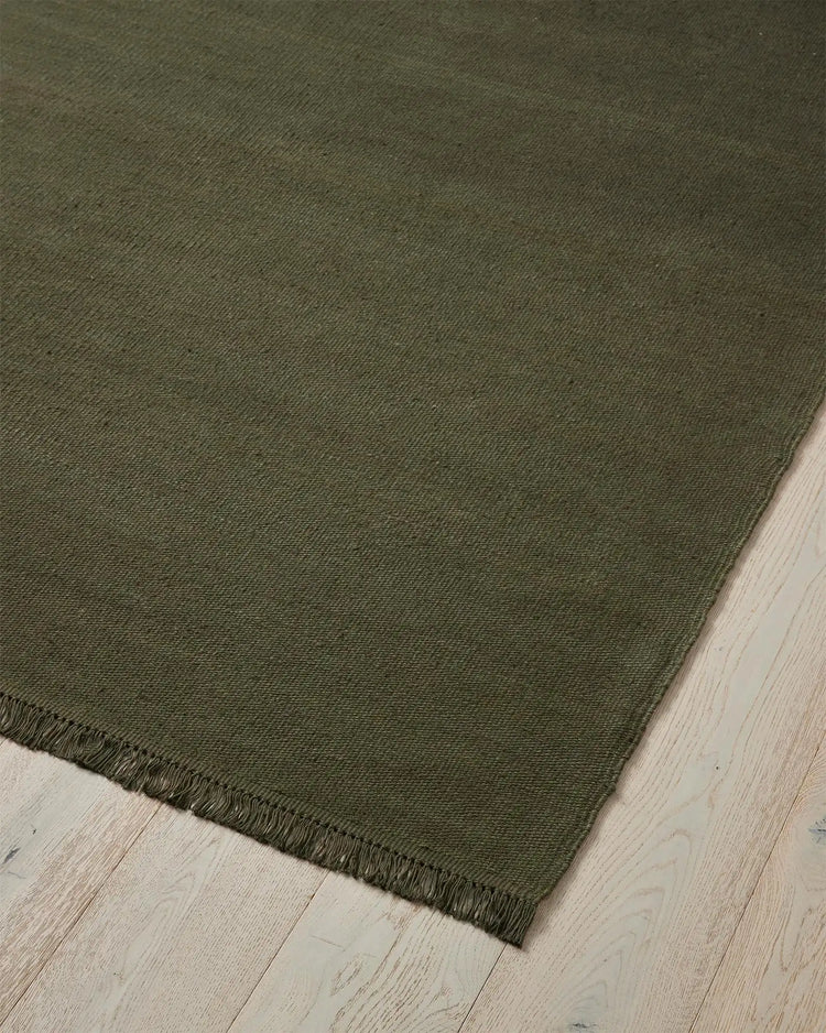 Emilio Kale linen rug corner detail, showing deep forest green flat-weave with fringe edge, 2m x 3m by Weave Home