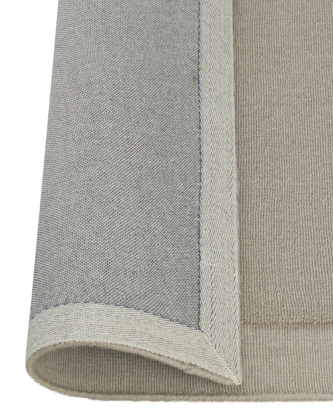 Cassio Fog rug detail showing tightly woven NZ wool loop pile with serged edge border in soft ecru by Weave Home