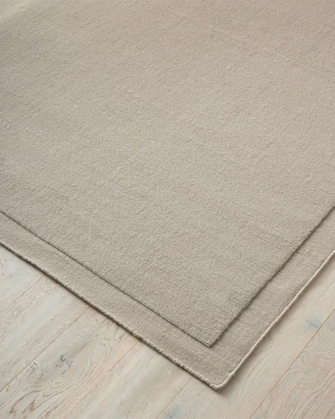 Cassio Fog 3x4m wool rug detail view, showing ecru tightly woven loop pile with hand-stitched serged edge by Weave Home