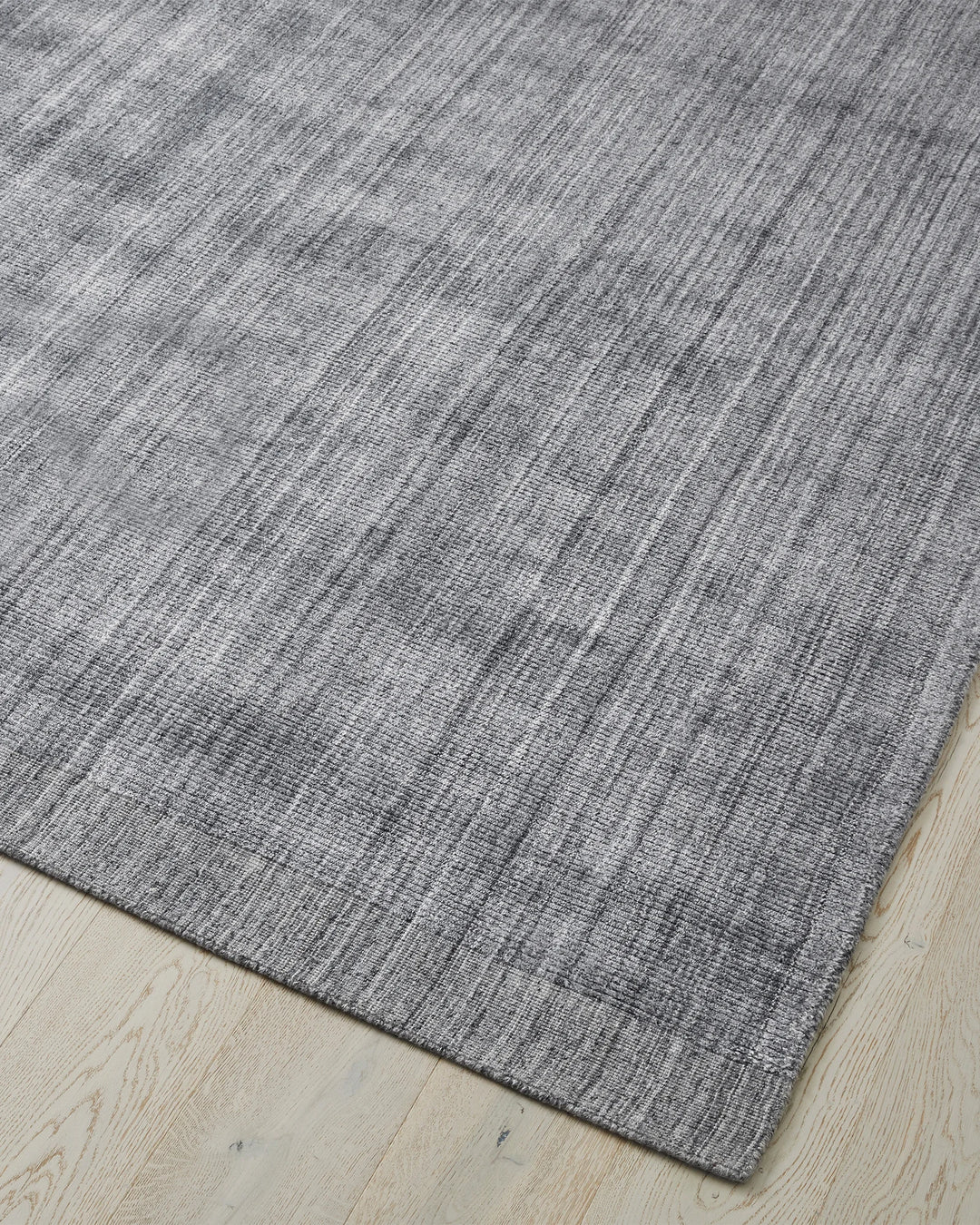 Travertine Pewter low-traffic rug corner view, showing hand-woven viscose blend with marbled texture and cotton backing, by Weave Home