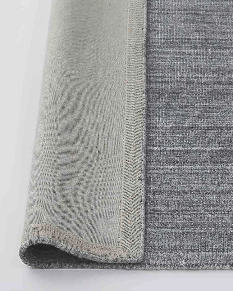 Travertine Pewter low-traffic rug, close-up of rolled edge showing viscose blend weave and cotton binding detail by Weave Home