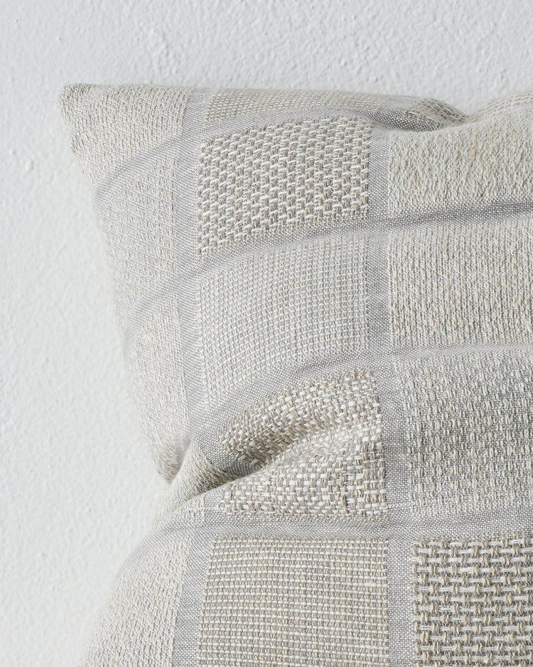 Bodrum Mist 50x50 cushion close-up, showing woven linen-cotton blend with geometric checkerboard panels and varied weave textures in soft blue tones by Weave Home