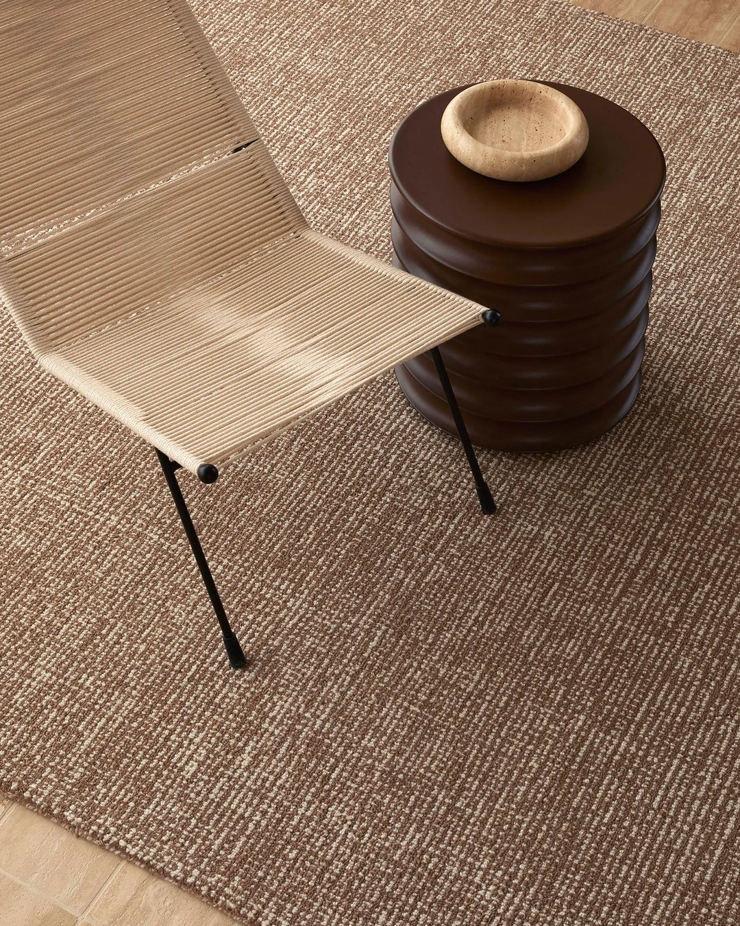 Neutral wool rug in mocha tone layered with natural wood furniture and ceramic accents, creating a warm, minimalist Scandinavian-inspired interior palette