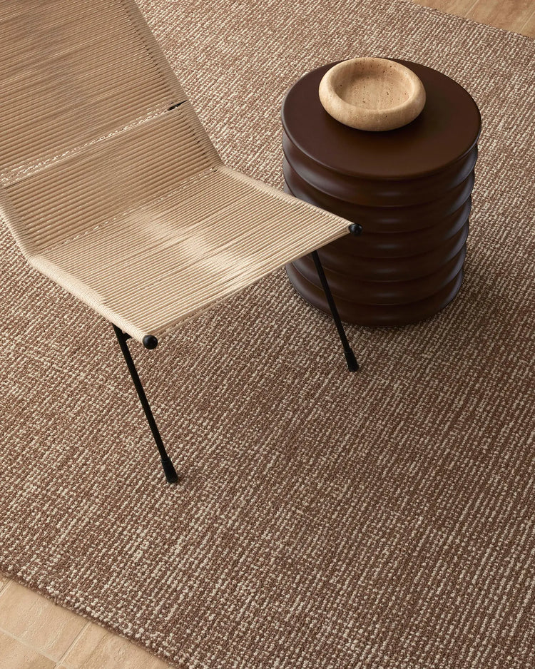 Neutral wool rug in mocha tone layered with natural wood furniture and ceramic accents, creating a warm, minimalist Scandinavian-inspired interior palette