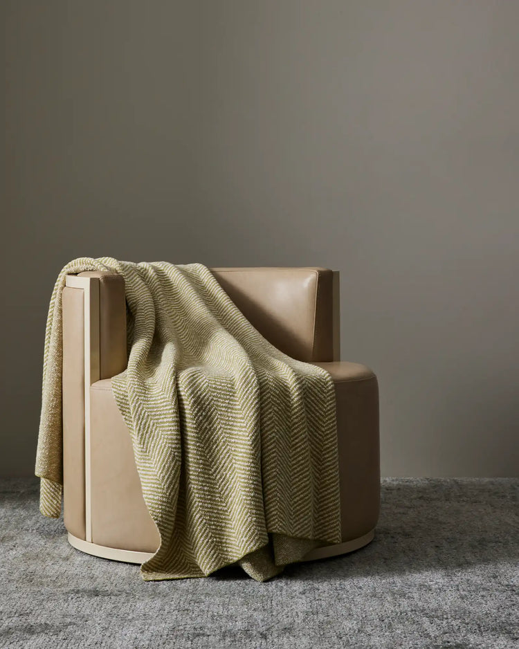 Solano Zest cotton throw with herringbone weave and bouclé reverse in citrus-toned green, draped over modern chair by Weave Home