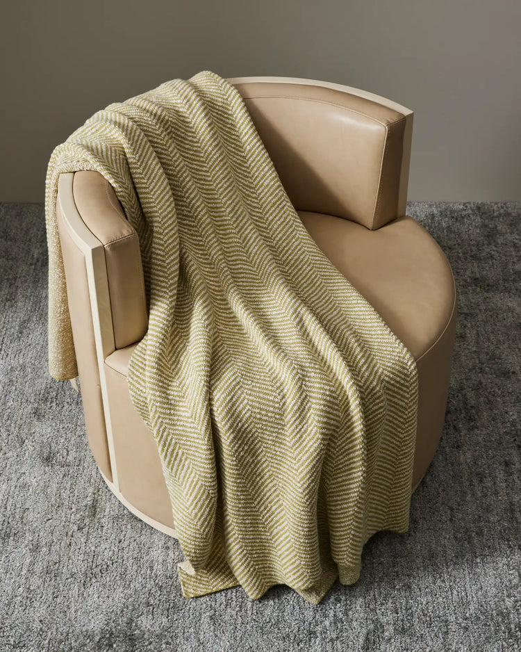 Solano Zest cotton throw draped over cream armchair, showing herringbone weave and bouclé reverse in citrus yellow by Weave Home