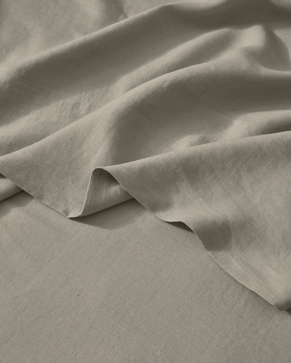 Close-up of soft pebble linen bedding with natural texture and folds, showing lightweight European linen weave in neutral warm tones