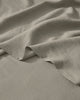 Close-up of soft pebble linen bedding with natural texture and folds, showing lightweight European linen weave in neutral warm tones