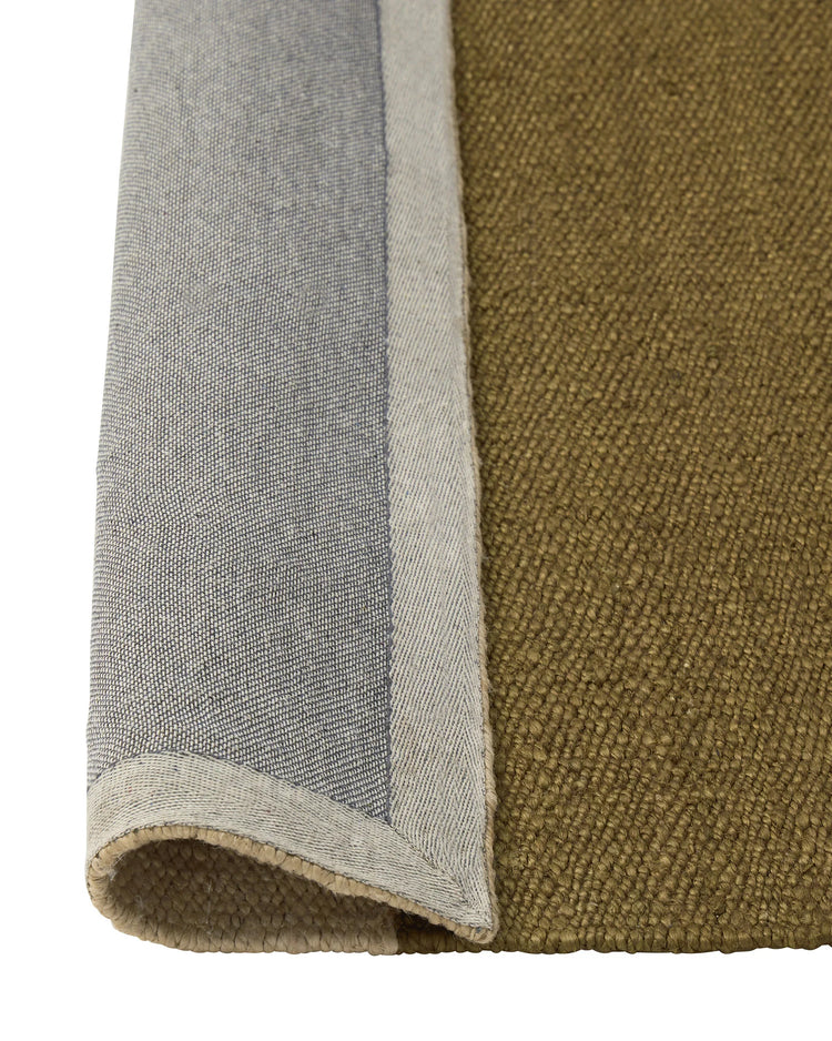 Ruben Terra rug detail, hand-woven jute in olive and charcoal with natural edge binding by Weave Home