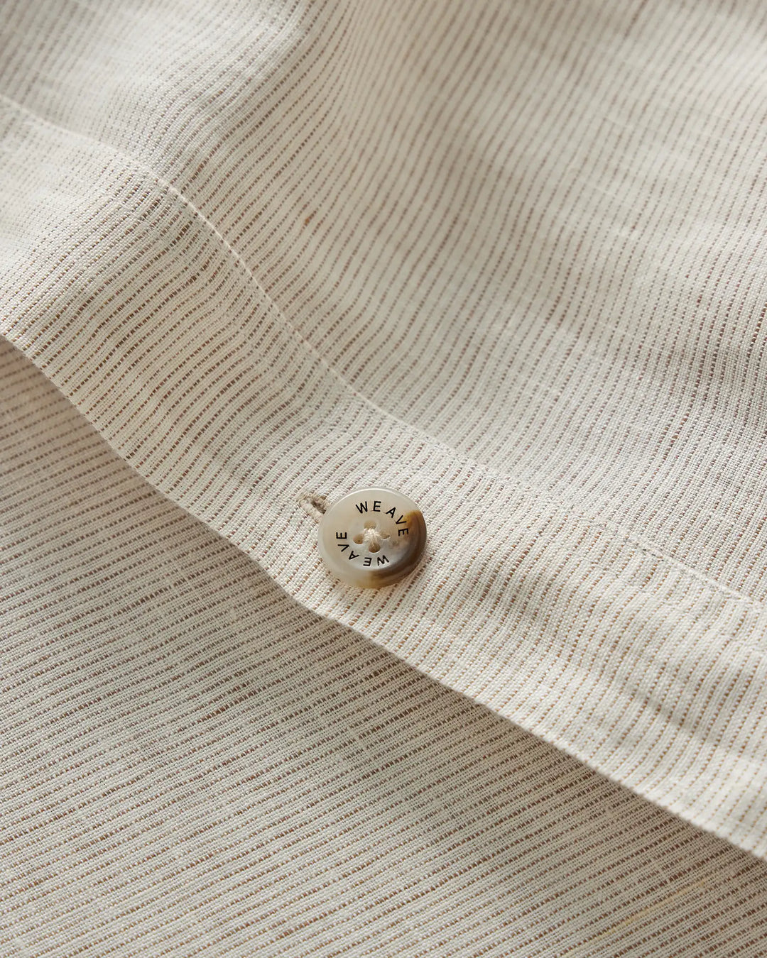 Sova Quilt Cover in Savanna Pinstripe, close-up detail of woven linen texture with branded button by Weave Home
