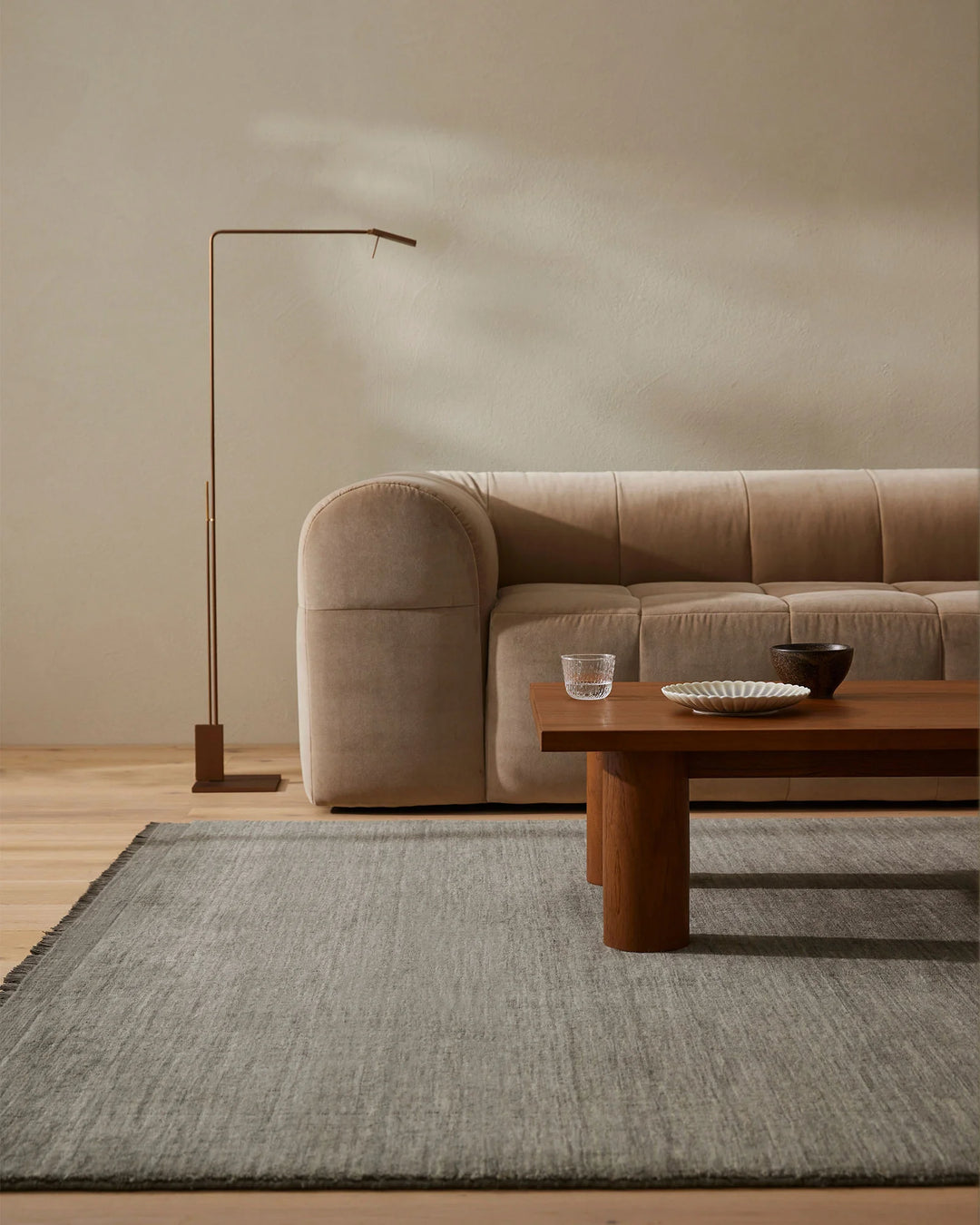 Minimalist living room with taupe upholstered sofa, wooden coffee table, and Silvio Fog high-traffic rug in soft greige tones anchoring the serene, neutral aesthetic
