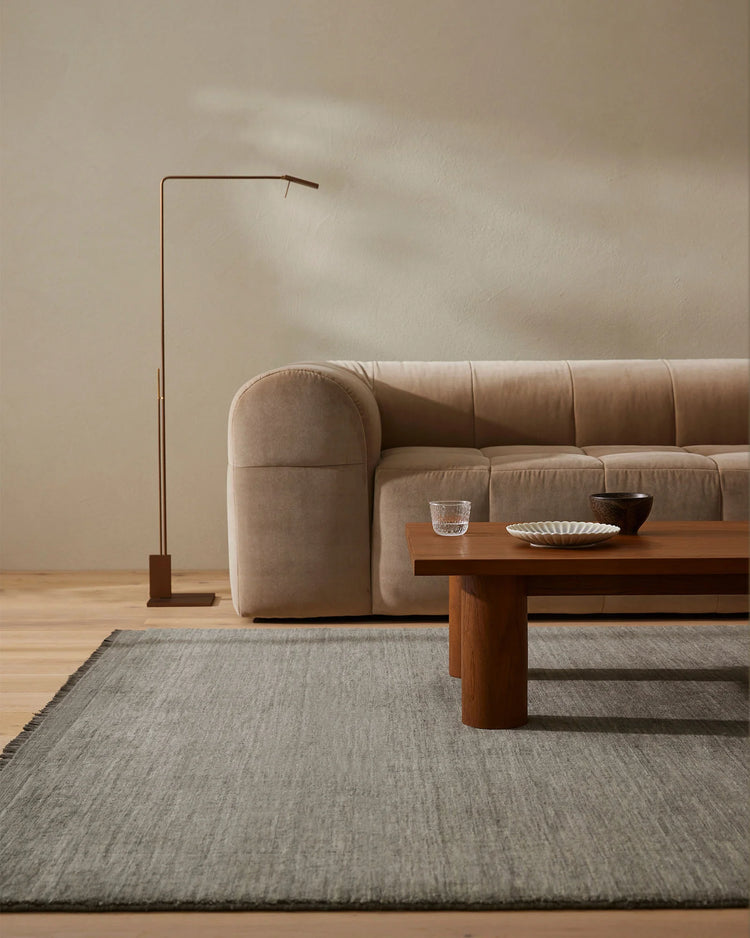 Minimalist living room with taupe upholstered sofa, wooden coffee table, and Silvio Fog high-traffic rug in soft greige tones anchoring the serene, neutral aesthetic