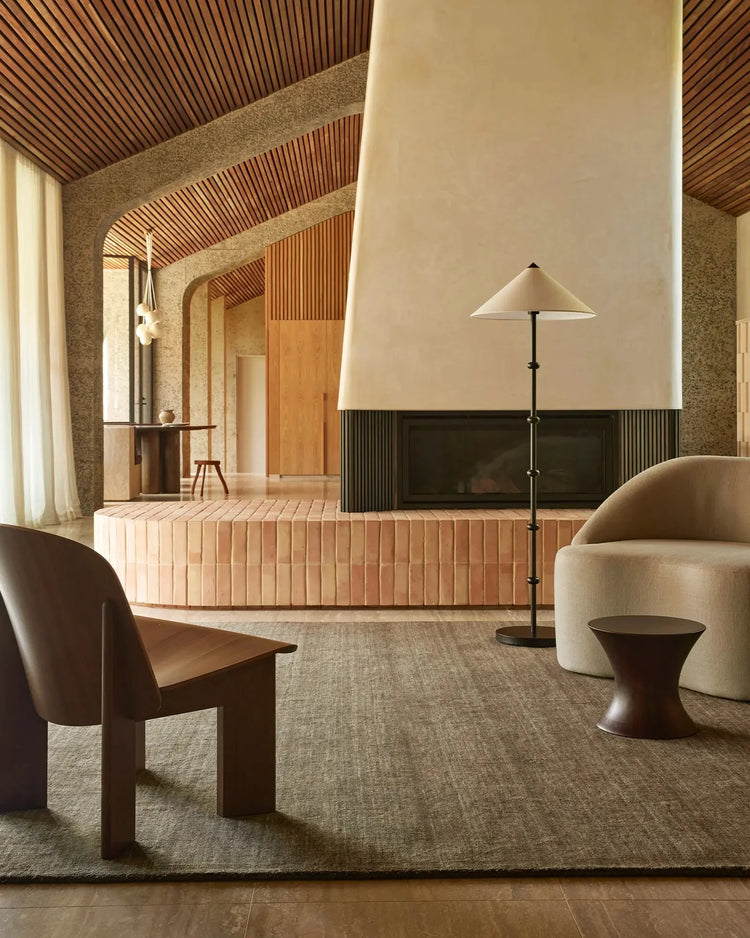 Warm minimalist living space with Silvio Fog rug anchoring earthy tones, natural wood, clay brick and fluted timber textures in japandi-inspired interior