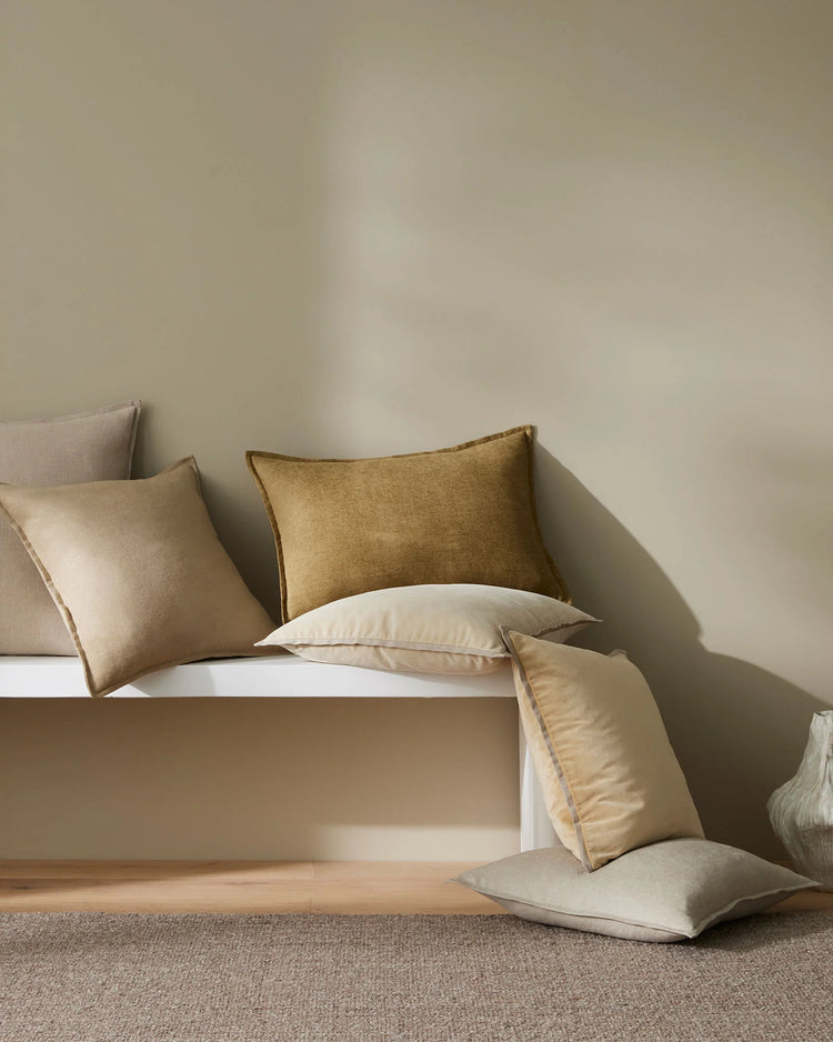 Neutral minimalist bedroom styling with Fiore cushions in ecru and sergeant tones, linen viscose textures layered on white bedding against soft greige walls and natural light