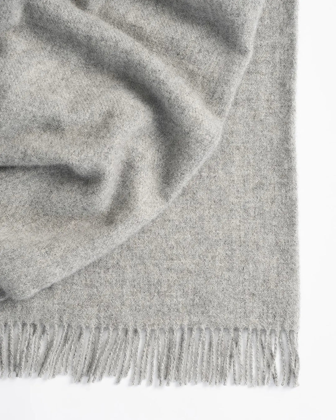 Nevis Ash lambswool throw in light steel grey, close-up detail of woven texture and tassel fringe border by Weave Home