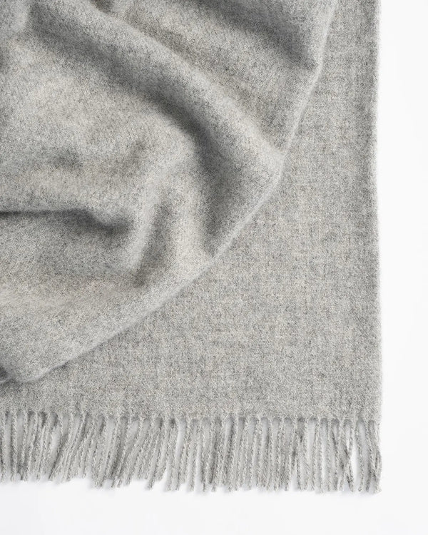 Nevis Ash lambswool throw in light steel grey, close-up detail of woven texture and tassel fringe border by Weave Home