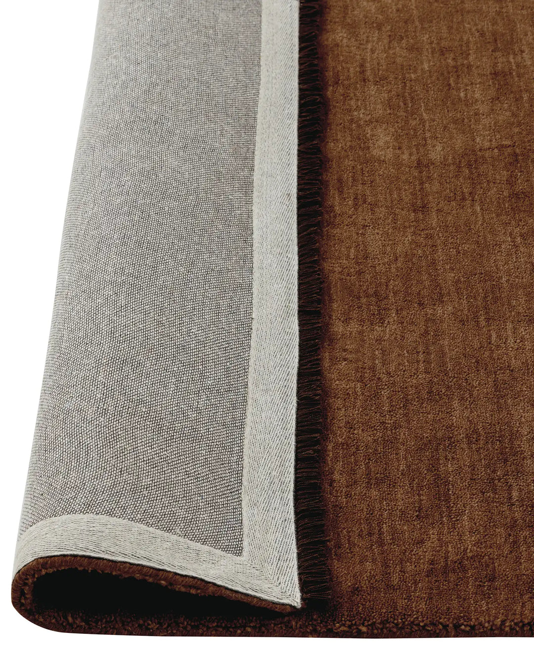Silvio Sienna rug detail view showing reddish-brown weave with micro fringe border and cream bound edge by Weave Home